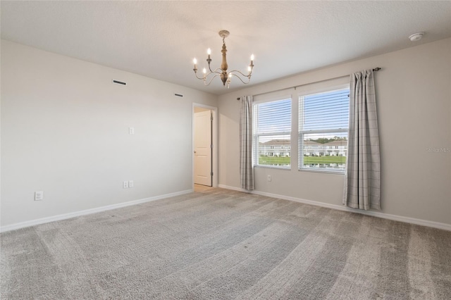 spare room featuring an inviting chandelier and carpet