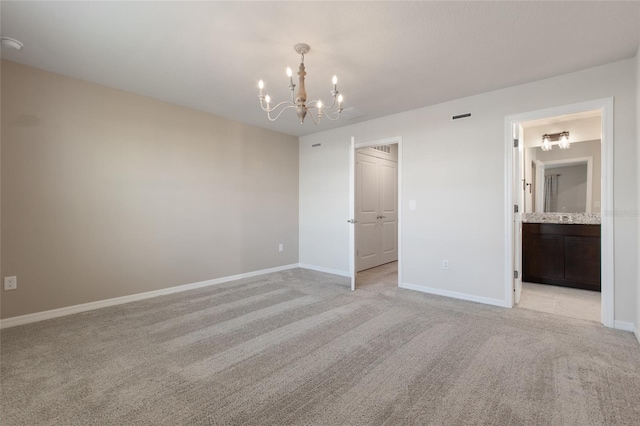 unfurnished bedroom with a closet, light carpet, ensuite bathroom, and a notable chandelier