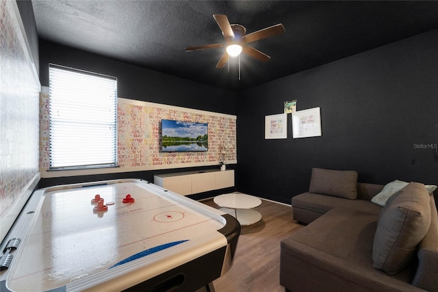 game room with wood-type flooring, a textured ceiling, and ceiling fan