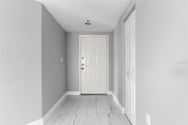 doorway to outside with a textured ceiling