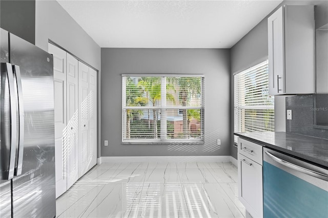 kitchen featuring appliances with stainless steel finishes, dark stone counters, and white cabinetry