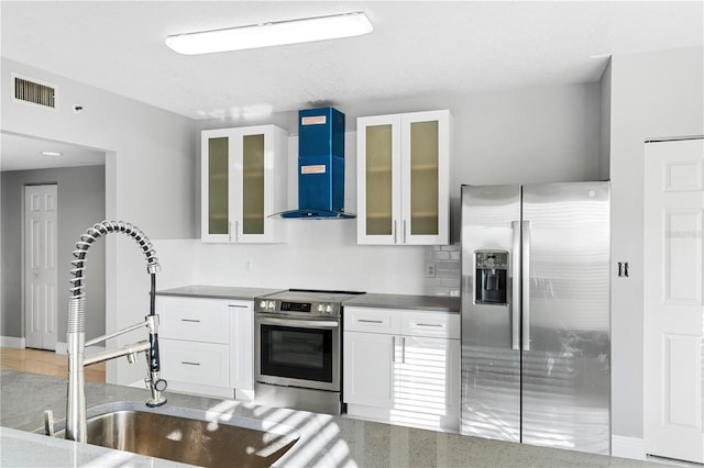 kitchen with white cabinets, sink, tasteful backsplash, wall chimney exhaust hood, and appliances with stainless steel finishes