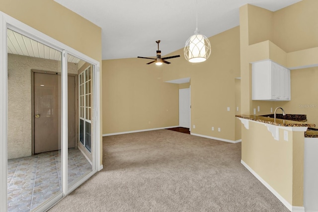 kitchen featuring hanging light fixtures, kitchen peninsula, high vaulted ceiling, white cabinetry, and light colored carpet