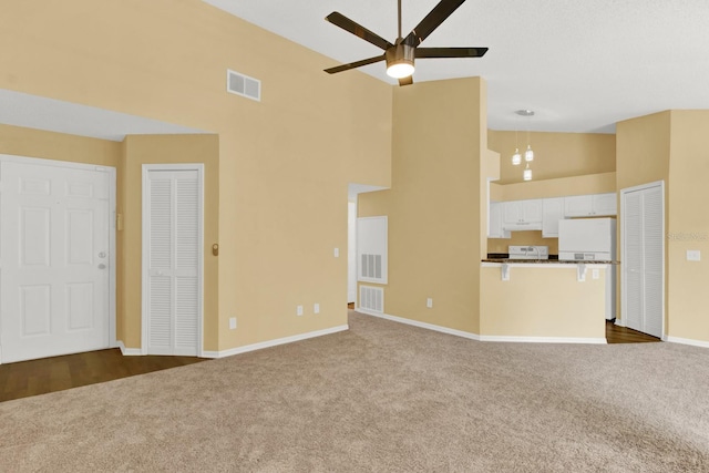 unfurnished living room featuring high vaulted ceiling, ceiling fan, and carpet floors