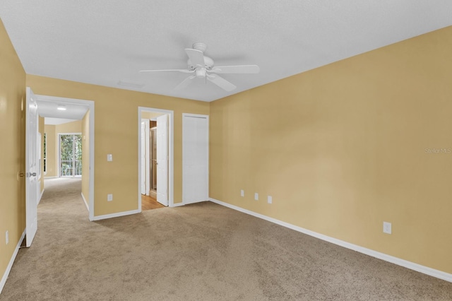 unfurnished bedroom with light carpet, a closet, ensuite bathroom, and ceiling fan