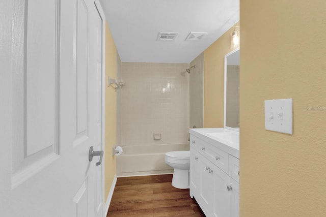 full bathroom with wood-type flooring, tiled shower / bath, vanity, and toilet