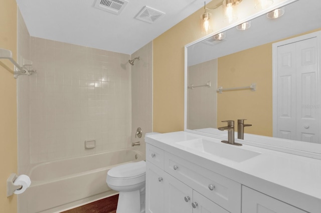 full bathroom with hardwood / wood-style flooring, tiled shower / bath combo, vanity, and toilet