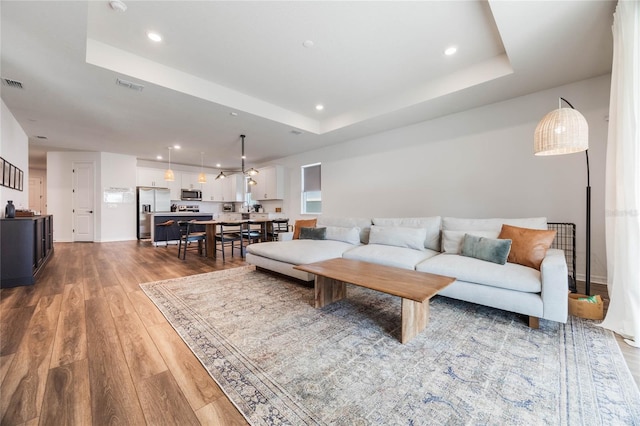 living room with a tray ceiling and hardwood / wood-style floors