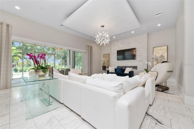 living room featuring a notable chandelier, a stone fireplace, and a healthy amount of sunlight