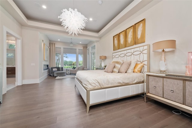 bedroom with dark wood-type flooring, a tray ceiling, and a chandelier