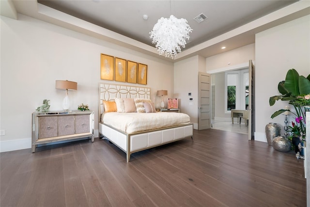 bedroom with a chandelier, a tray ceiling, and dark hardwood / wood-style flooring