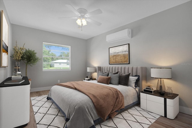 bedroom with ceiling fan, a wall mounted AC, and light wood-type flooring