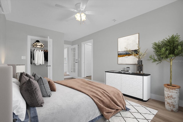 bedroom with ceiling fan, a spacious closet, and light hardwood / wood-style flooring