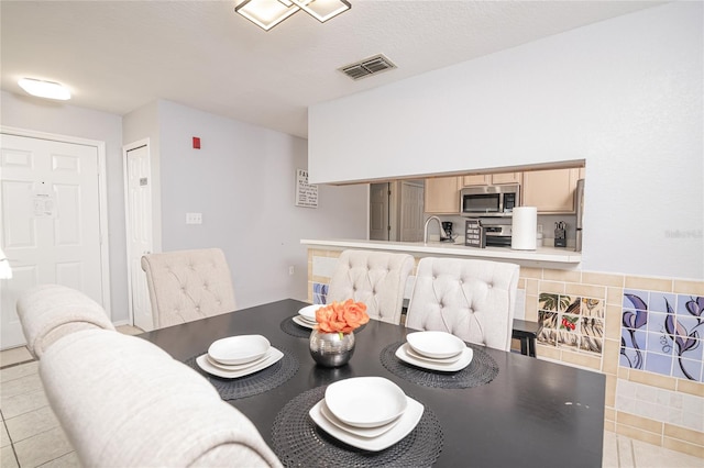 dining space with light tile patterned floors and sink