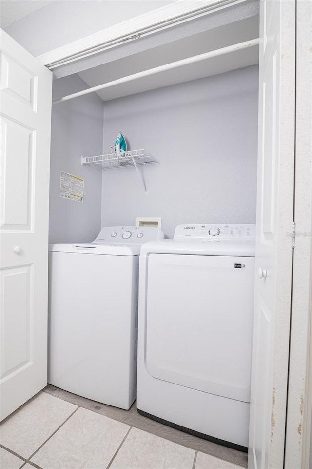 clothes washing area featuring washing machine and clothes dryer and light tile patterned flooring