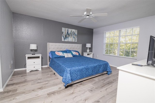 bedroom featuring light wood-type flooring, a textured ceiling, and ceiling fan