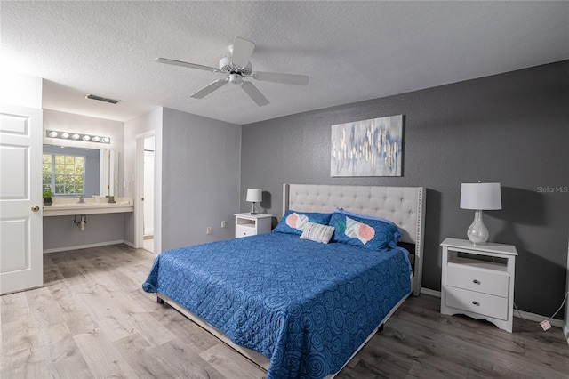 bedroom with a textured ceiling, wood-type flooring, ceiling fan, and ensuite bathroom