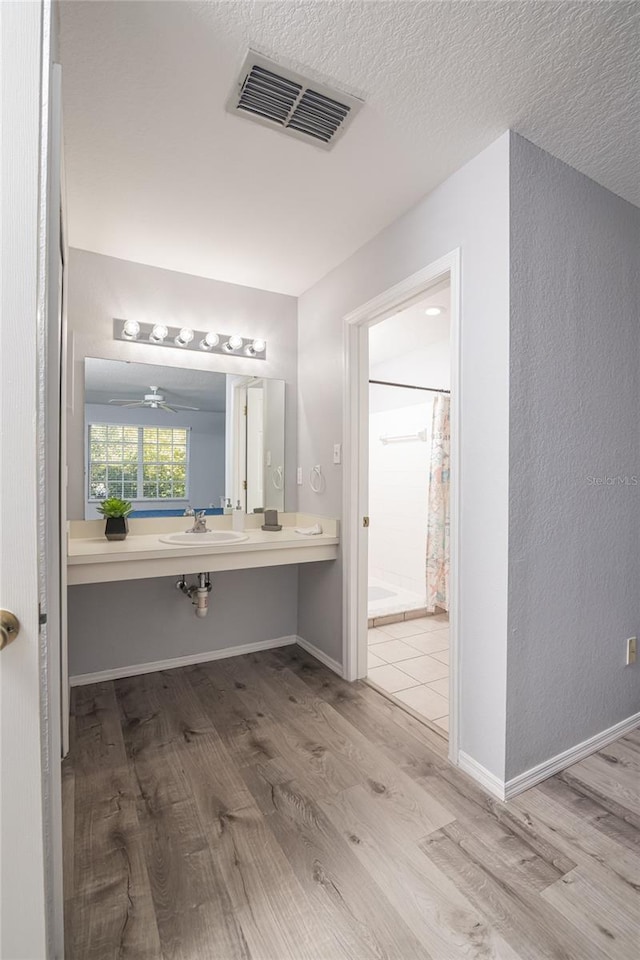 bathroom with a textured ceiling, wood-type flooring, ceiling fan, sink, and a shower with curtain