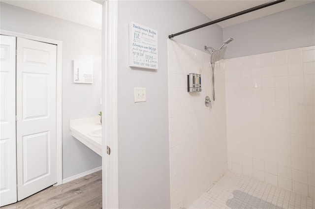 bathroom featuring wood-type flooring and a tile shower