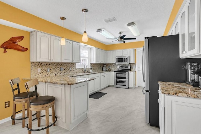 kitchen with kitchen peninsula, sink, stainless steel appliances, and white cabinets