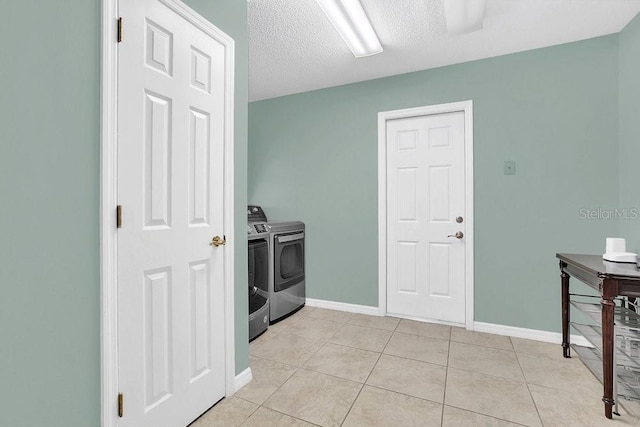 washroom with a textured ceiling, light tile patterned floors, and washing machine and dryer