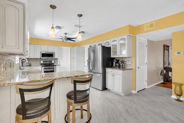 kitchen featuring decorative backsplash, white cabinetry, kitchen peninsula, stainless steel appliances, and sink