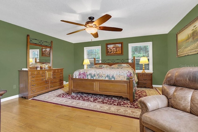 bedroom with light hardwood / wood-style floors, ceiling fan, and a textured ceiling