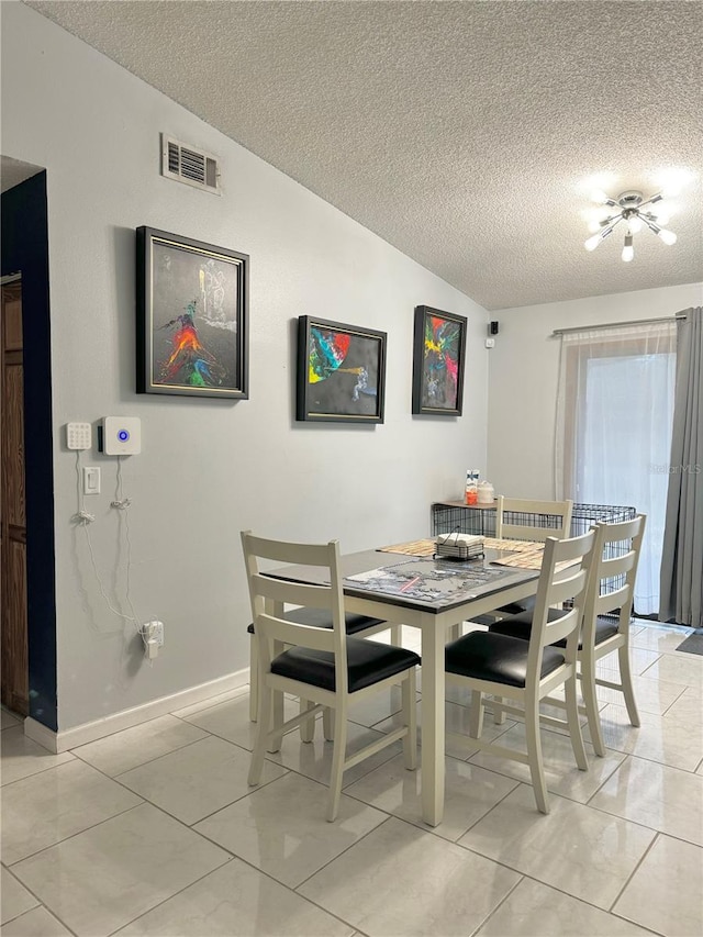 dining room featuring a textured ceiling, lofted ceiling, and light tile patterned floors