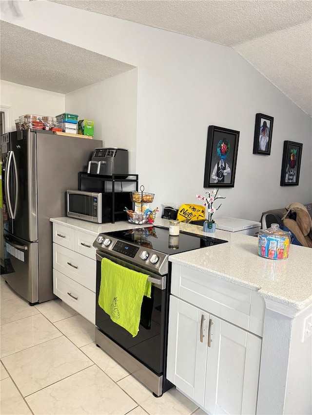 kitchen with a textured ceiling, white cabinets, lofted ceiling, kitchen peninsula, and appliances with stainless steel finishes