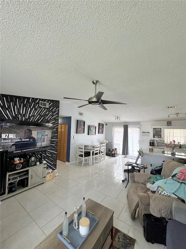 living room with a textured ceiling, light tile patterned floors, and ceiling fan