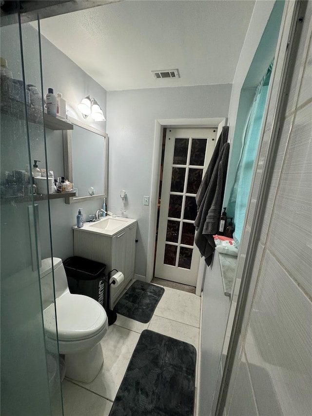 bathroom featuring tile patterned flooring, a shower with door, vanity, and toilet