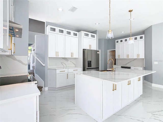 kitchen with white cabinetry, stainless steel refrigerator with ice dispenser, sink, and a center island with sink