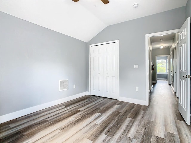 unfurnished bedroom featuring lofted ceiling, ceiling fan, a closet, and dark hardwood / wood-style flooring