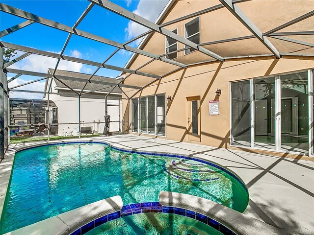 view of pool with a patio area, an in ground hot tub, and glass enclosure