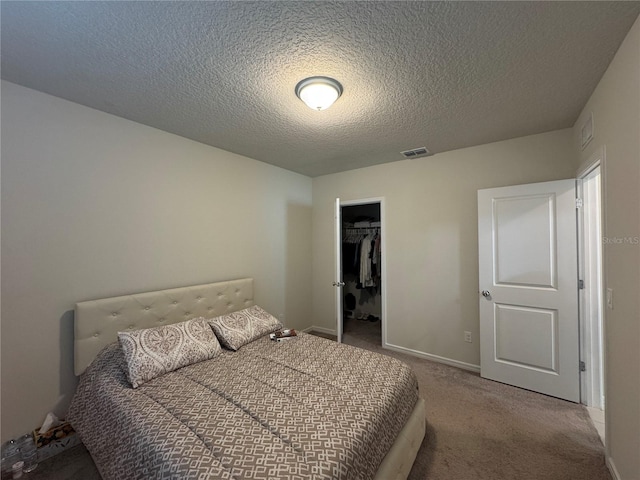 carpeted bedroom with a textured ceiling, a spacious closet, and a closet