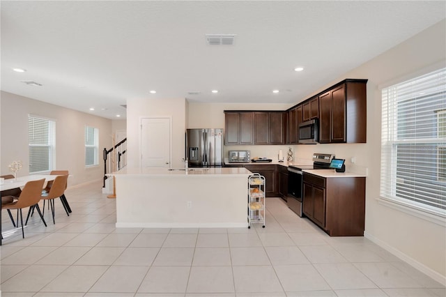 kitchen with dark brown cabinets, a kitchen island, a healthy amount of sunlight, and appliances with stainless steel finishes