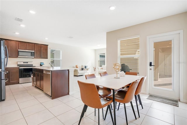 dining area with sink, light tile patterned floors, and a healthy amount of sunlight