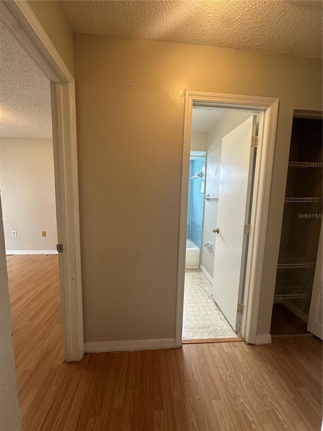 hallway with wood-type flooring and a textured ceiling