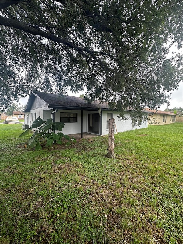 rear view of property featuring a yard and a patio area