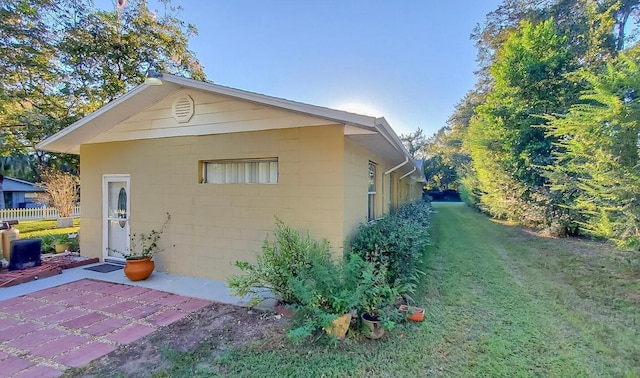1501 NE 57th St, Ocala, FL 34479 - view of side of home featuring a patio, concrete block siding, and a lawn