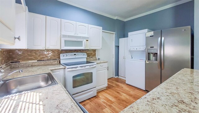 1501 NE 57th St, Ocala, FL 34479 - kitchen featuring white appliances, a sink, white cabinetry, stacked washing maching and dryer, and light wood-type flooring