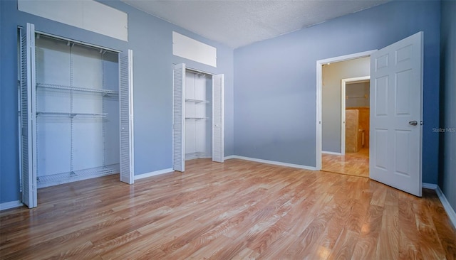 1501 NE 57th St, Ocala, FL 34479 - unfurnished bedroom with a textured ceiling, two closets, baseboards, and light wood-style floors