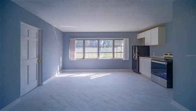 1501 NE 57th St, Ocala, FL 34479 - kitchen featuring a sink, freestanding refrigerator, white cabinetry, baseboards, and stainless steel electric stove