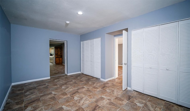 1501 NE 57th St, Ocala, FL 34479 - unfurnished bedroom featuring two closets, baseboards, stone finish floor, and recessed lighting