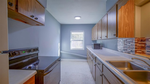 1501 NE 57th St, Ocala, FL 34479 - kitchen with baseboards, stainless steel microwave, a sink, tasteful backsplash, and electric range