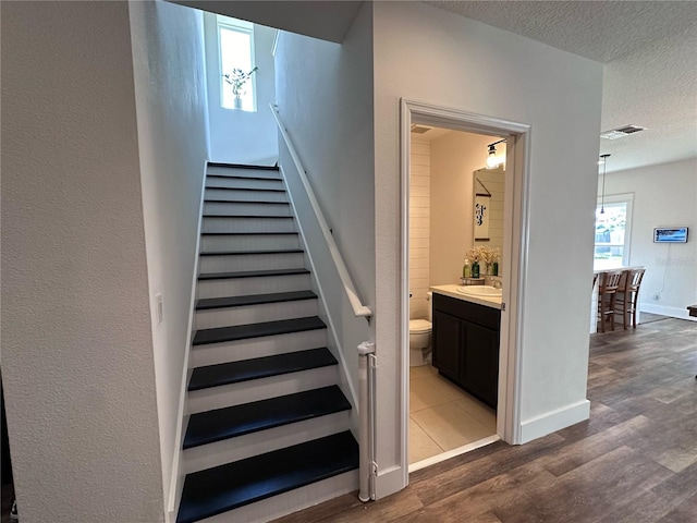 stairs featuring a textured ceiling, sink, and hardwood / wood-style flooring