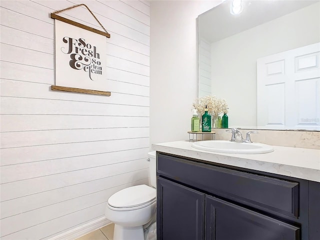 bathroom with vanity, wood walls, toilet, and tile patterned flooring