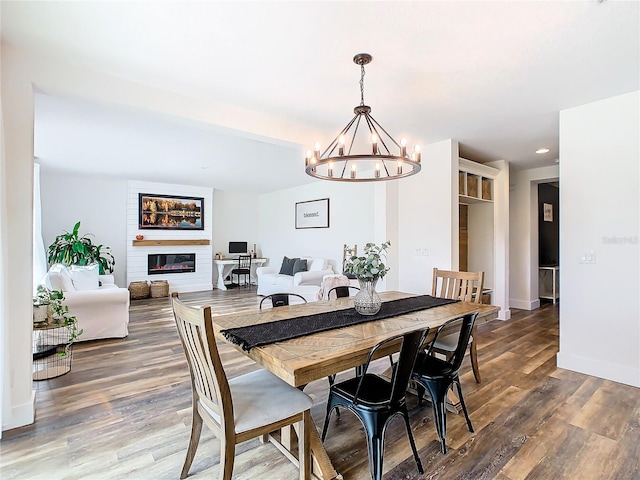 dining room with an inviting chandelier, a fireplace, and dark hardwood / wood-style flooring