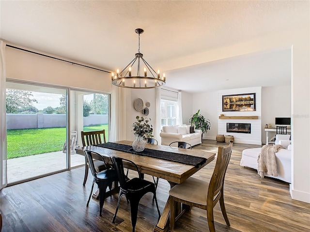 dining room featuring wood-type flooring, a chandelier, and a fireplace