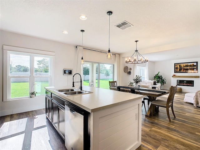 kitchen featuring decorative light fixtures, stainless steel dishwasher, a kitchen island with sink, and a wealth of natural light